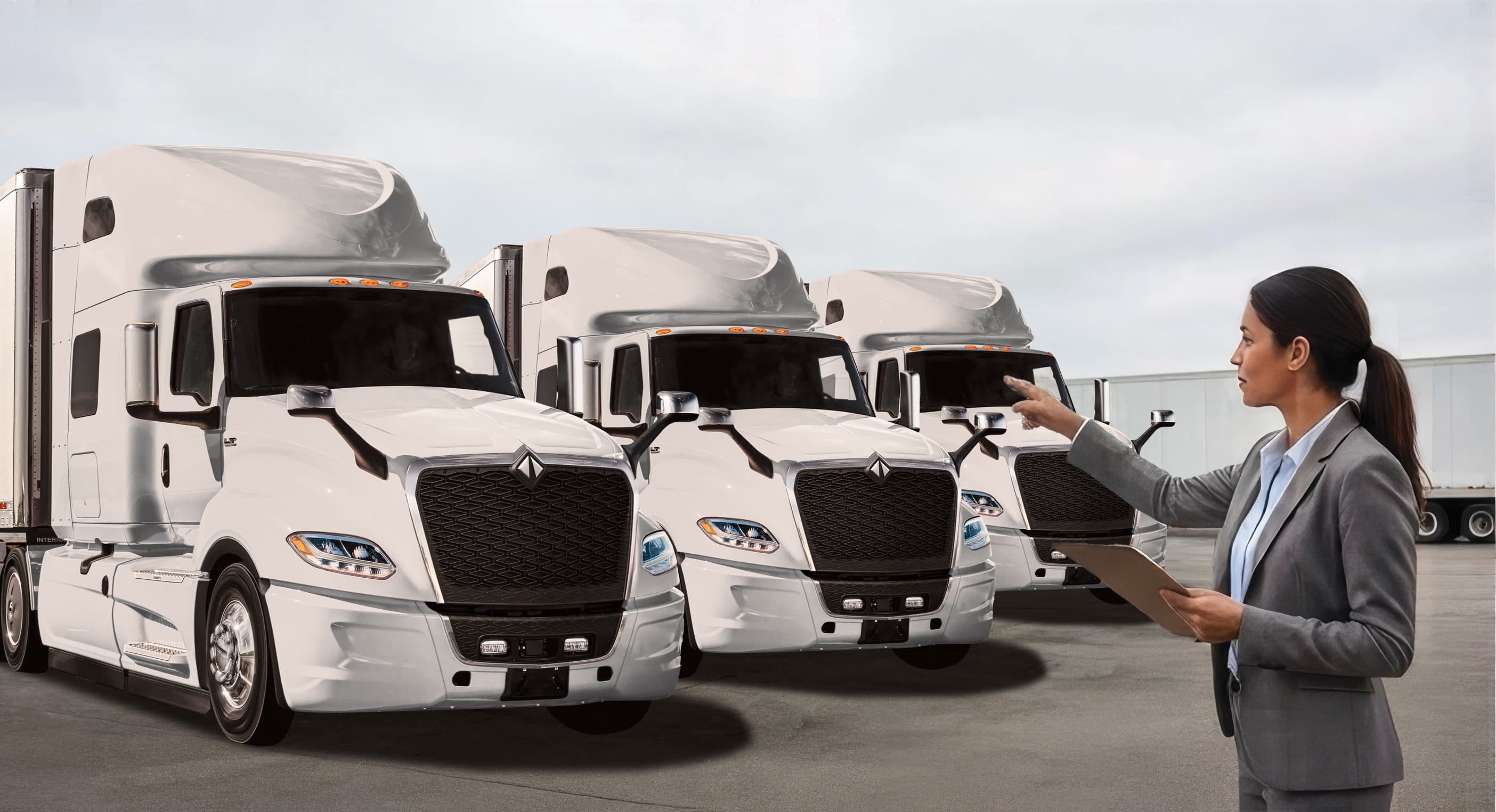 Woman Pointing to Line of White International Truck Sleeper Cabs